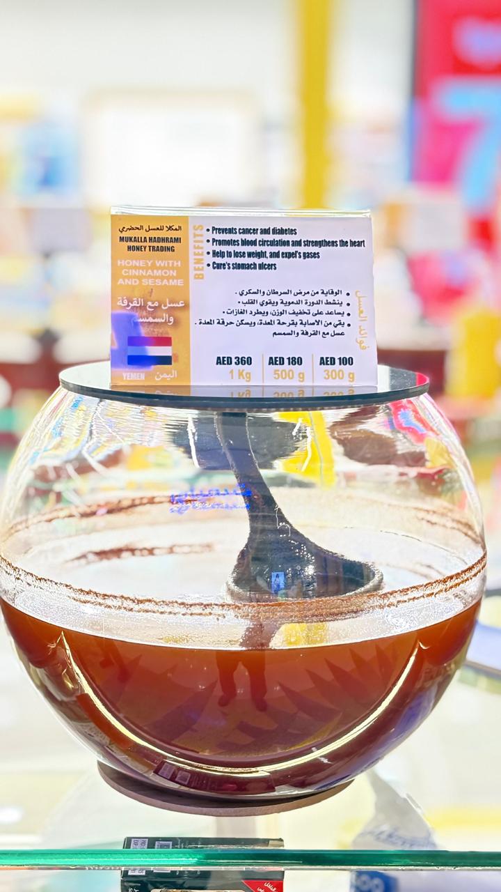Honey with cinnamon and sesame in a spherical glass jar with branded label.