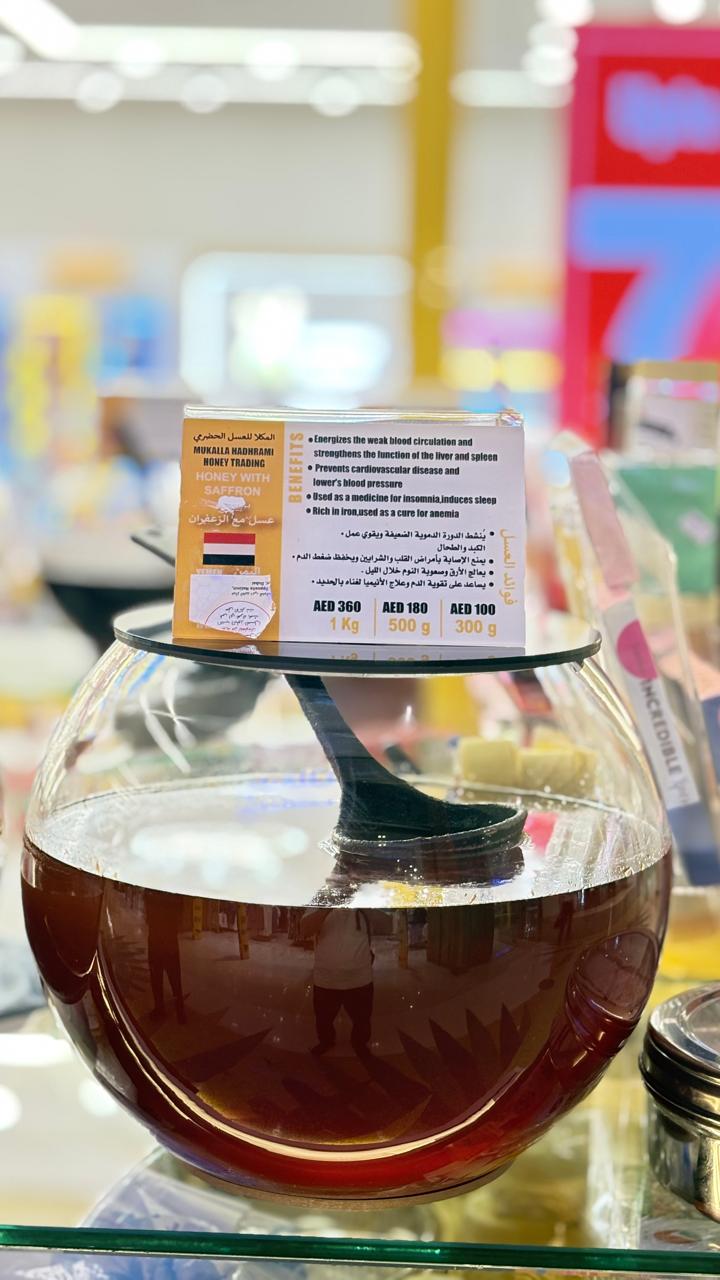 Honey with saffron in a spherical glass jar with branded label.