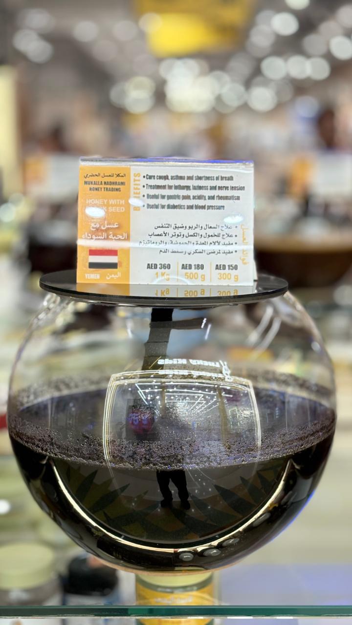 Honey with black seed in a spherical glass jar with branded label.
